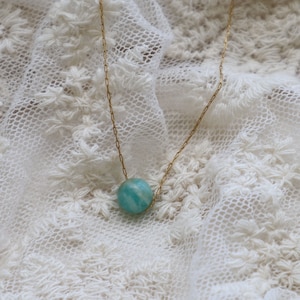 May include: A gold chain necklace with a single round blue-green gemstone pendant.