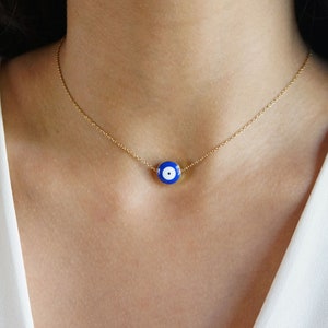 Peut inclure: Un collier en cha&icirc;ne dor&eacute;e avec un pendentif &oelig;il turc bleu et blanc.