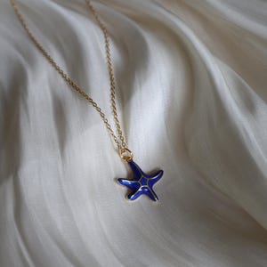 May include: A gold chain necklace with a blue enamel starfish pendant.