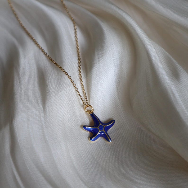 May include: A gold chain necklace with a blue enamel starfish pendant.