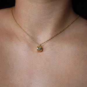 May include: A gold chain necklace with a small, square pendant shaped like a padlock.