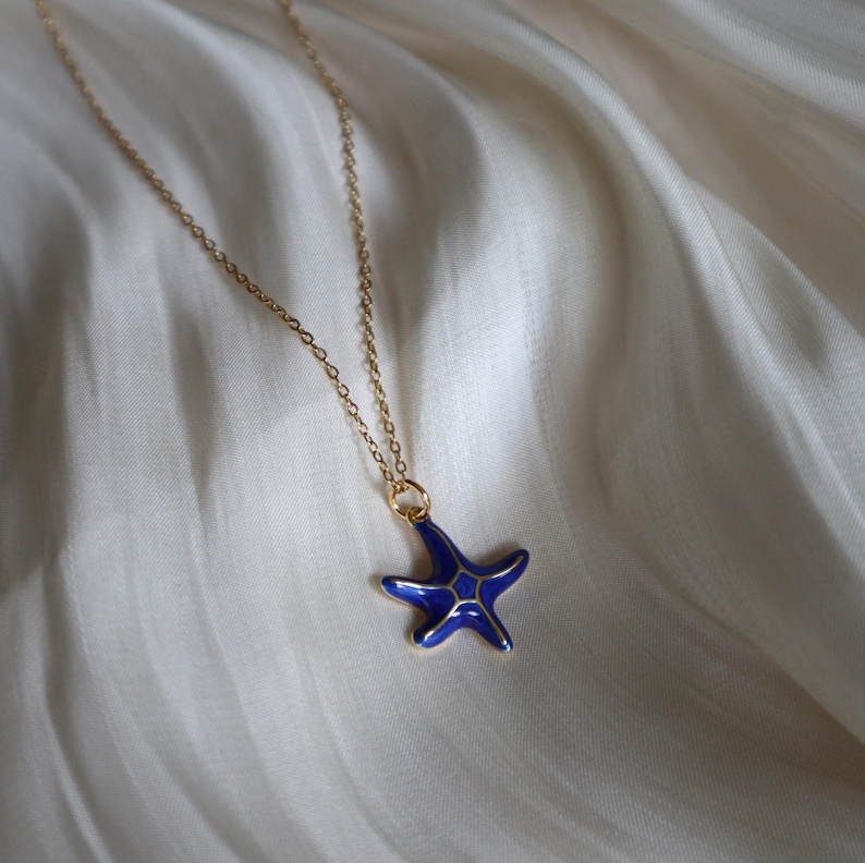 May include: A gold chain necklace with a blue enamel starfish pendant.