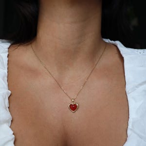 May include: A gold chain necklace with a red heart pendant.