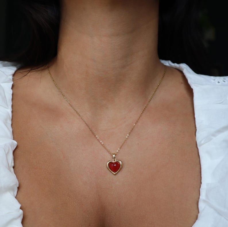 May include: A gold chain necklace with a red heart pendant.