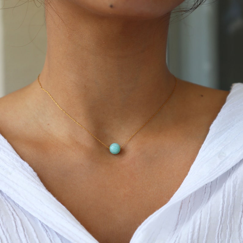 May include: A delicate gold chain necklace with a single turquoise gemstone bead pendant.