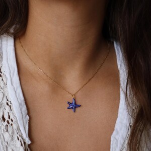 May include: A gold chain necklace with a blue ceramic starfish pendant.