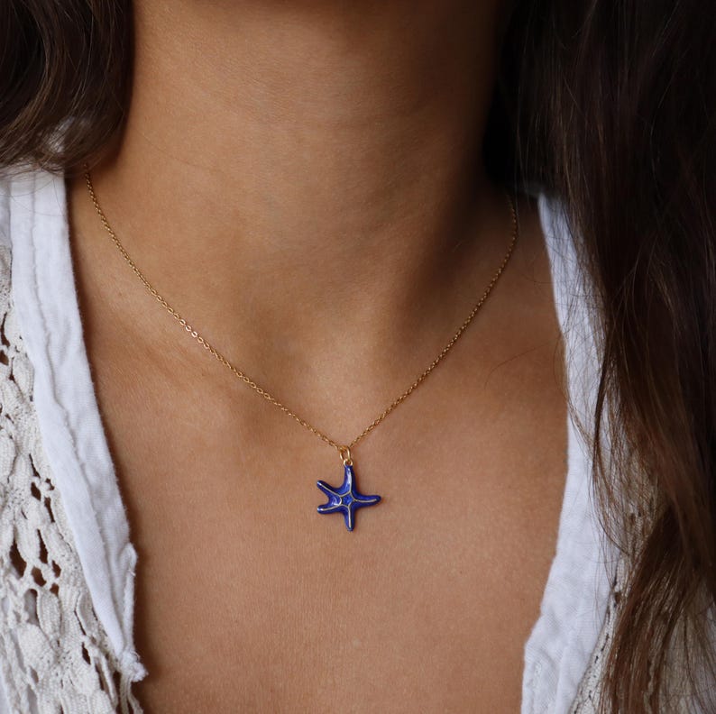 May include: A gold chain necklace with a blue ceramic starfish pendant.