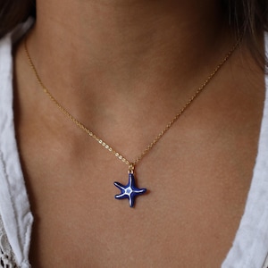 May include: A gold chain necklace with a blue enamel starfish pendant.