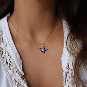 May include: A gold chain necklace with a blue enamel starfish pendant.