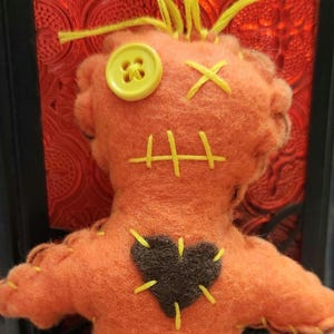 Donald Trump Poppet Voodoo Doll, 6"tall, orange body, blonde hair, dark brown heart. He arrives with 2 pins to get you started. Doll is made of felt, cotton thread, fiber fill and button eye.
