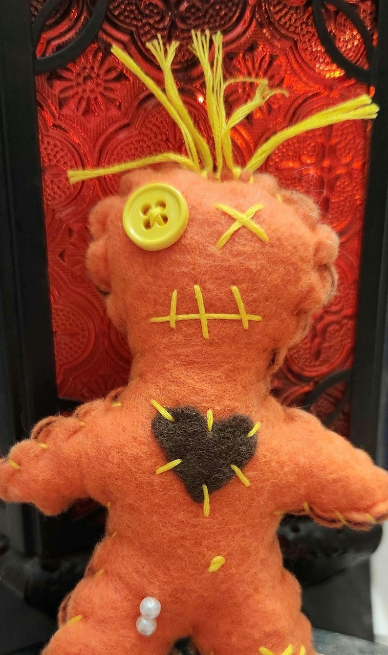 Donald Trump Poppet Voodoo Doll, 6"tall, orange body, blonde hair, dark brown heart. He arrives with 2 pins to get you started. Doll is made of felt, cotton thread, fiber fill and button eye.