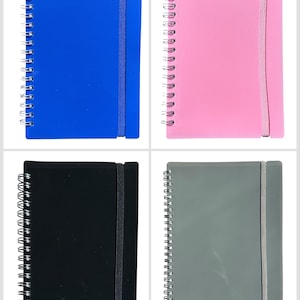 May include: Four spiral-bound notebooks in blue, pink, black, and grey. Each notebook has a textured cover and an elastic band closure. The notebooks are arranged in a square formation against a white background.
