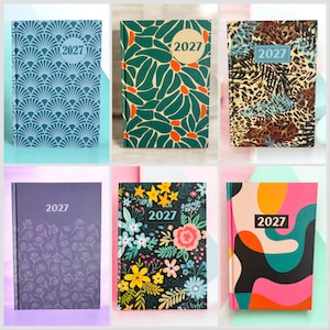 May include: A selection of 2027 planners with diverse cover designs. The covers display patterns such as art deco, floral, and animal print. Colours include blue, green, purple, black, and pink. Each planner has the year "2027" printed on the cover.
