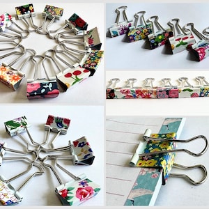May include: A set of 20 binder clips with colourful floral patterns. The clips are made of metal and have a spring-loaded mechanism. They are arranged in a circle and a line, with some clips also shown being used to hold papers together.