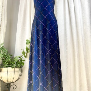 May include: A strapless, floor-length gown in a deep blue color with a diamond-shaped pattern of purple and gold sequins.