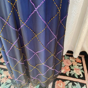 May include: A navy blue maxi dress with a diamond pattern of purple and gold beads.