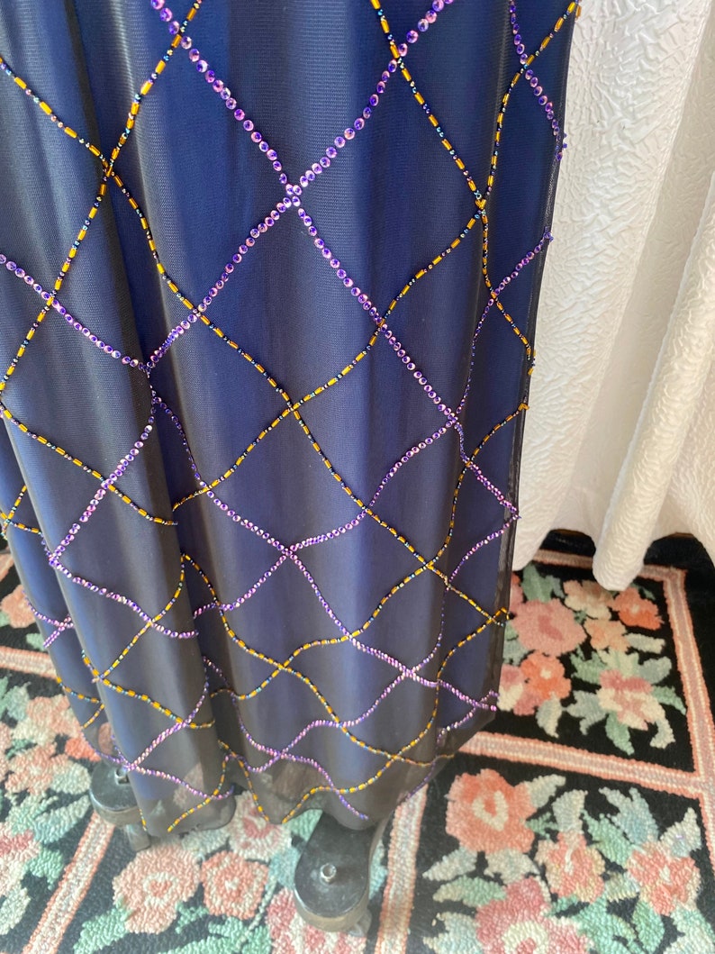 May include: A navy blue maxi dress with a diamond pattern of purple and gold beads.