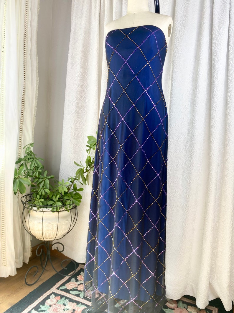 May include: A long, strapless, navy blue gown with a diamond-shaped pattern of sequins in gold and purple.