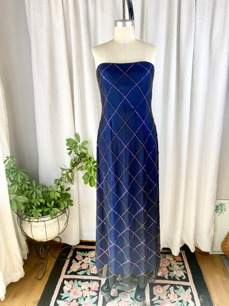 May include: A strapless, floor-length, navy blue gown with a diamond-shaped pattern of gold and purple sequins.