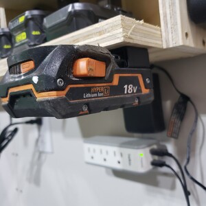May include: A black and orange 18V lithium-ion battery charger with the text "HYPER Li" and "Lithium Ion" on it.