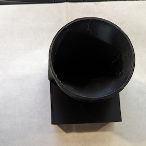 May include: A black plastic 3D printed funnel with a square base and a round opening.