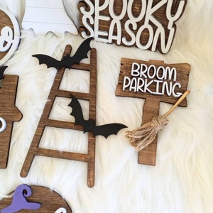 May include: Wooden Halloween decorations with a spooky season sign, a broom parking sign, a ladder with bats, and a witch sign.