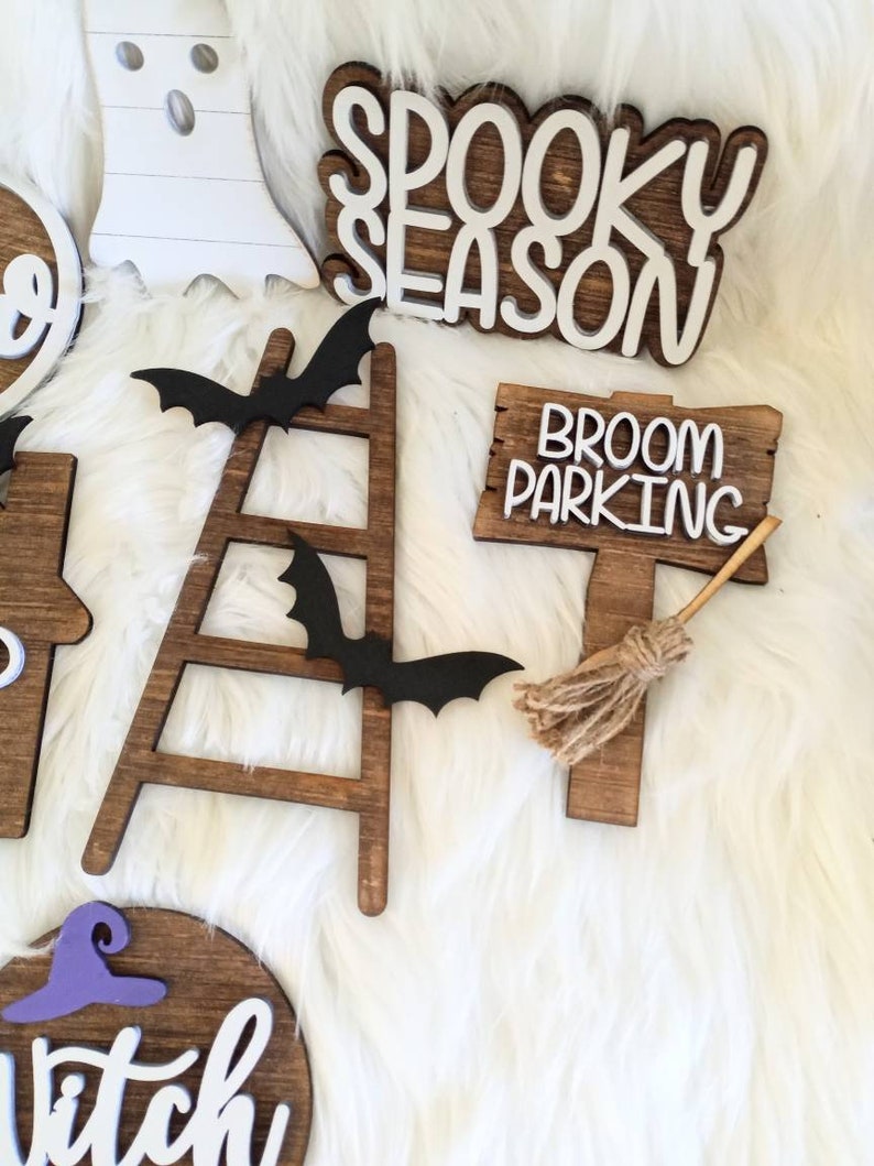 May include: Wooden Halloween decorations with a spooky season sign, a broom parking sign, a ladder with bats, and a witch sign.