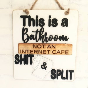 May include: White wooden sign with black lettering that reads "This is a Bathroom Not an Internet Cafe" with a black and white toilet paper roll graphic and the words "Shit & Split" below.