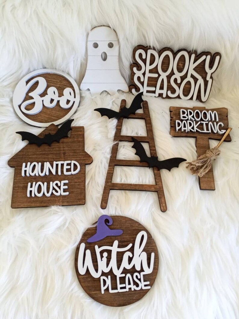 May include: A set of seven wooden Halloween signs with white lettering. The signs include "Boo", "Spooky Season", "Haunted House", "Broom Parking", "Witch Please", and two bats.