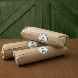 Puede incluir: Tres paquetes envueltos en papel marr&oacute;n con un logotipo de oveja blanca y el texto "Green Fleece" en cada paquete.