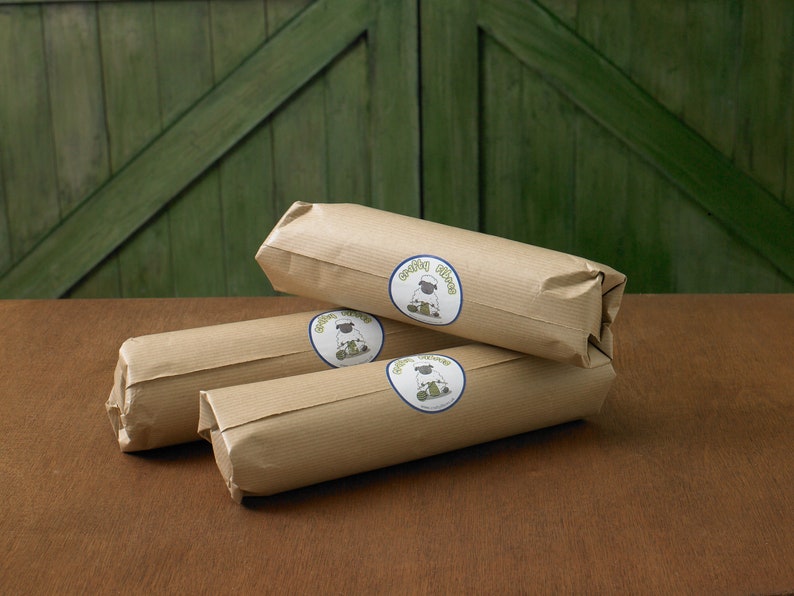 Puede incluir: Tres paquetes envueltos en papel marr&oacute;n con un logotipo de oveja blanca y el texto "Green Fleece" en cada paquete.