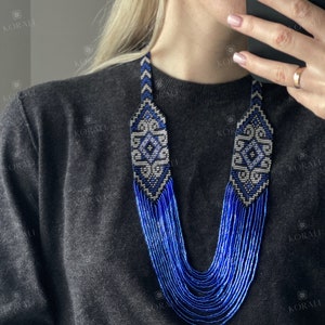 May include: A long, layered necklace made of blue and white beads. The necklace features a geometric pattern in the center.