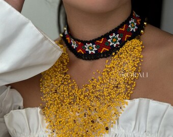 May include: A beaded necklace with a black choker base and a colorful geometric pattern. The necklace is made of small yellow beads that cascade down the front of the neck.