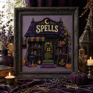 Könnte beinhalten: Eine gerahmte Kreuzstichstickerei, die ein Ladenlokal mit dem Wort SPELLS in großen Buchstaben über dem Eingang darstellt. Das Design zeigt eine violette und schwarze Farbpalette, einen Halbmond, Zaubertrankflaschen, einen Besen und ein Hexenhut-Schild.
