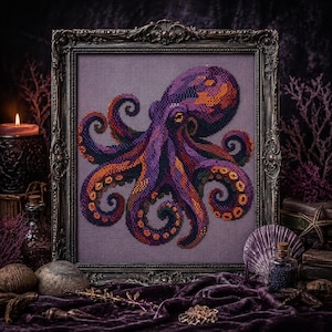 May include: A cross-stitch embroidery of an octopus in shades of purple, orange, and black, displayed within an ornate, dark metallic frame. The octopus features detailed tentacles with visible suction cups, set against a solid grey fabric background.