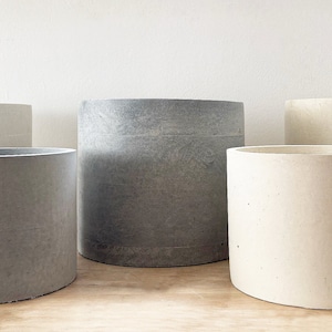 May include: Five concrete planters in different sizes, two are grey and three are white.