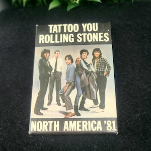 Peut inclure: Une cassette audio avec une photo en noir et blanc des membres du groupe The Rolling Stones sur la face avant. Le texte "Tattoo You Rolling Stones North America '81" est imprimé sur la cassette.