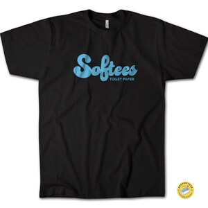 Könnte beinhalten: Schwarzes T-Shirt mit dem Wort "Softees" in hellblauer Schrift, darüber die Worte "Toilet Paper" in kleinerer Schrift. Das T-Shirt hat einen Rundhalsausschnitt.