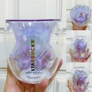May include: A clear glass mug with a purple iridescent finish and a paw print design. The mug has the Starbucks logo and the words "Warm Wishes" printed on it.