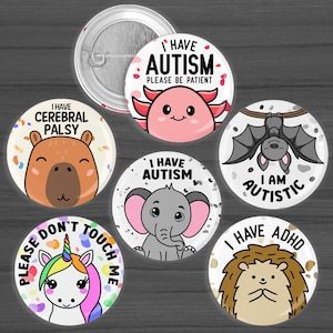 May include: A collection of round pinback buttons with various cartoon animal illustrations and text. The buttons feature an axolotl, elephant, bat, hedgehog, unicorn, and capybara. Text includes "I Have Autism," "I Have Cerebral Palsy," and "Please Don't Touch Me."