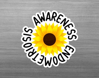 Pode incluir: Um adesivo circular com um girassol amarelo vibrante e um centro castanho escuro. O texto 'ENDOMETRIOSIS AWARENESS' está impresso em letras maiúsculas pretas e negrito, curvando-se em torno do girassol numa borda branca.