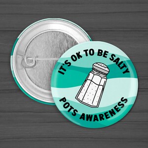 Puede incluir: Un bot&oacute;n azul verdoso y blanco con el texto "It's OK to be Salty" y un gr&aacute;fico de un salero. El texto "POTS Awareness" tambi&eacute;n est&aacute; en el bot&oacute;n.
