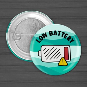 Puede incluir: Un bot&oacute;n a rayas azul turquesa y blanco con el texto "LOW BATTERY" en negro. Un icono de bater&iacute;a blanco con una barra roja y un signo de exclamaci&oacute;n amarillo se encuentra en el centro del bot&oacute;n.