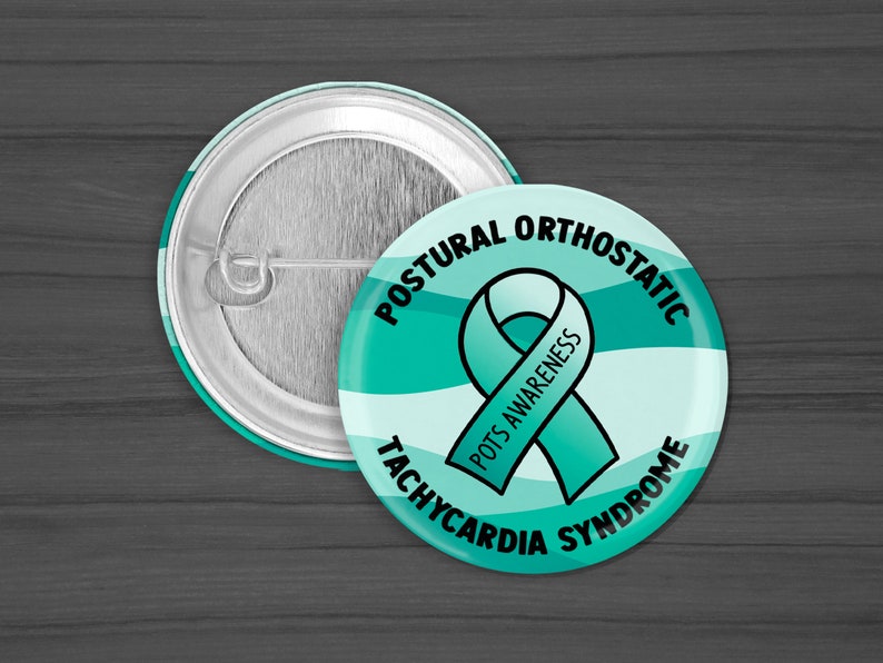 Puede incluir: Bot&oacute;n azul verdoso y blanco con el texto "Postural Orthostatic Tachycardia Syndrome" y una cinta azul verdosa con el texto "POTS Awareness".