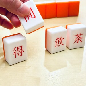 A hand picking up a custom mahjong tile.