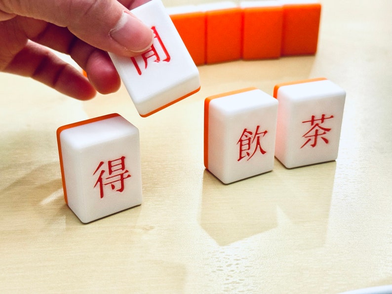 A hand picking up a custom mahjong tile.