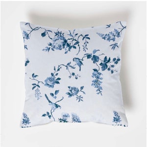 May include: A white cushion with a blue floral pattern featuring birds and roses.