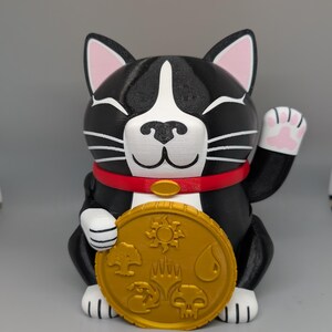 May include: A black and white cat figurine with pink inner ears and paw pads, wearing a red collar with a gold oval charm. The cat holds a large, round, gold-colored coin featuring five distinct embossed symbols representing various magical elements.