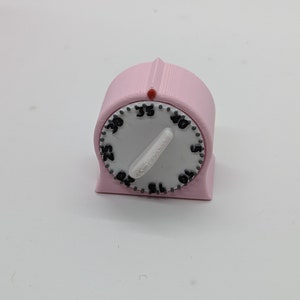Könnte beinhalten: Ein rosa Küchen-Timer mit weißem Zifferblatt und schwarzen Zahlen. Der Timer ist auf 35 Minuten eingestellt.