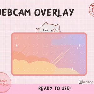 May include: A digital webcam overlay featuring a rectangular frame with a gradient pink and orange sky background, clouds, and stars. A white cat character peeks over the top edge. Text includes WEBCAM OVERLAY, DMON AT WORK, INSTANT DOWNLOAD, and READY TO USE!